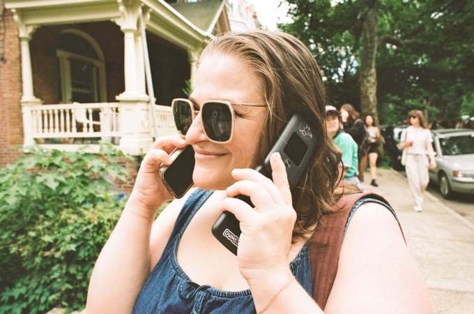 The author using an iPhone and a Dumb Phone