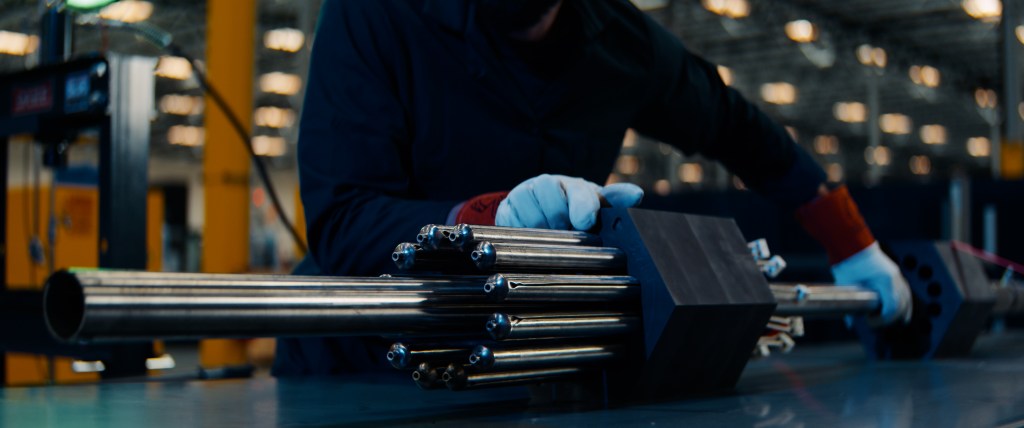 A person handles a nuclear fuel assembly.