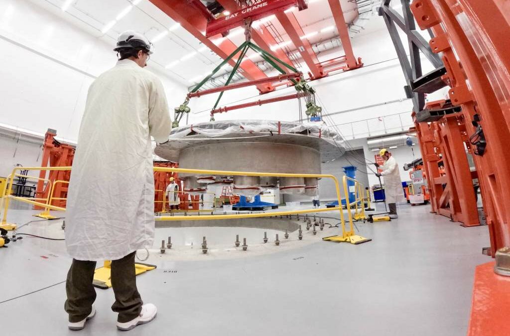 Commonwealth Fusion Systems employees supervise the installation of the tokamak's cryostat base.