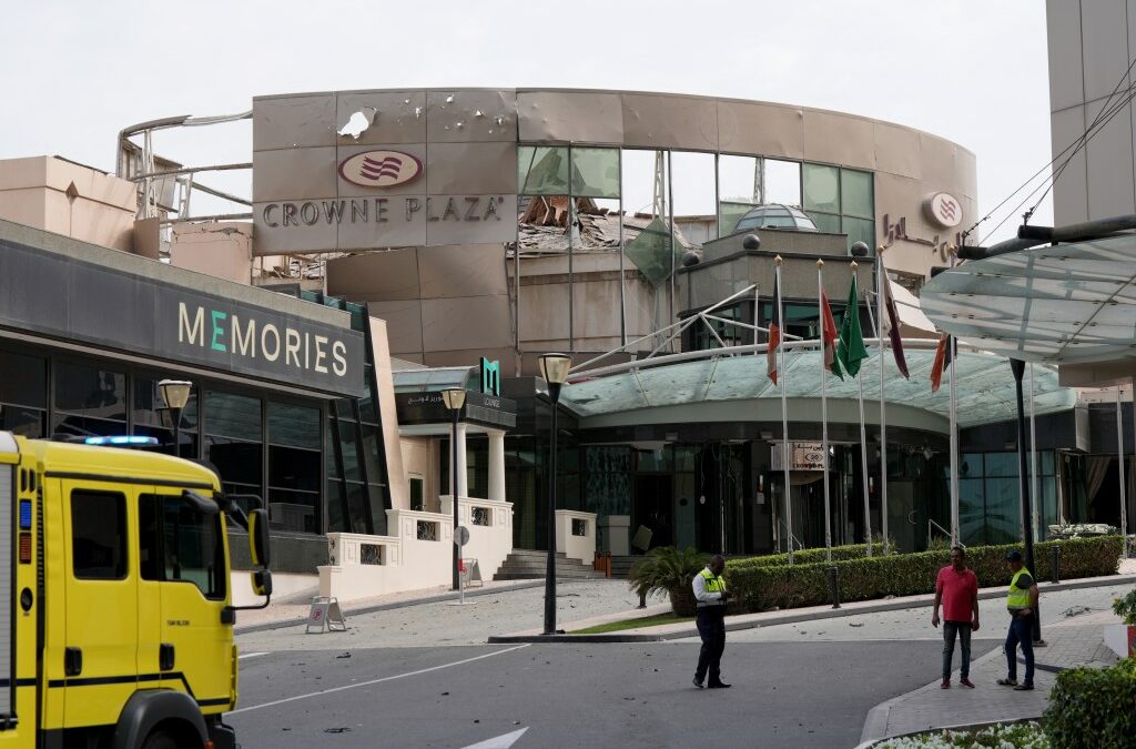 Security and civil defense workers stand outside the damaged Crown Plaza hotel, following an Iranian military strike, in Manama on March 1, 2026.