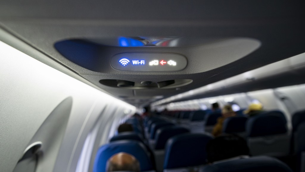 A Wi-Fi and fasten seat belts sign illuminated on a Delta Air Lines plane.