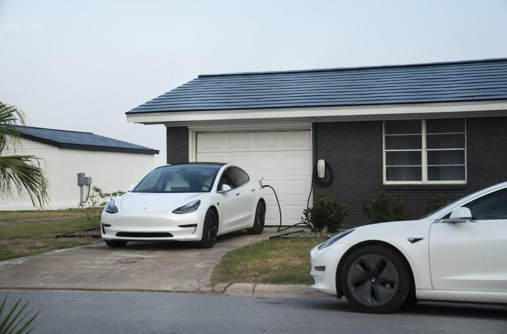 Tesla vehicles parked outside a home with a Tesla Solar Roof.