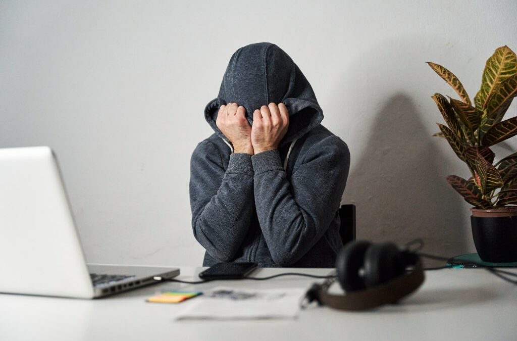 Man covering his face with a hood while working from home.
