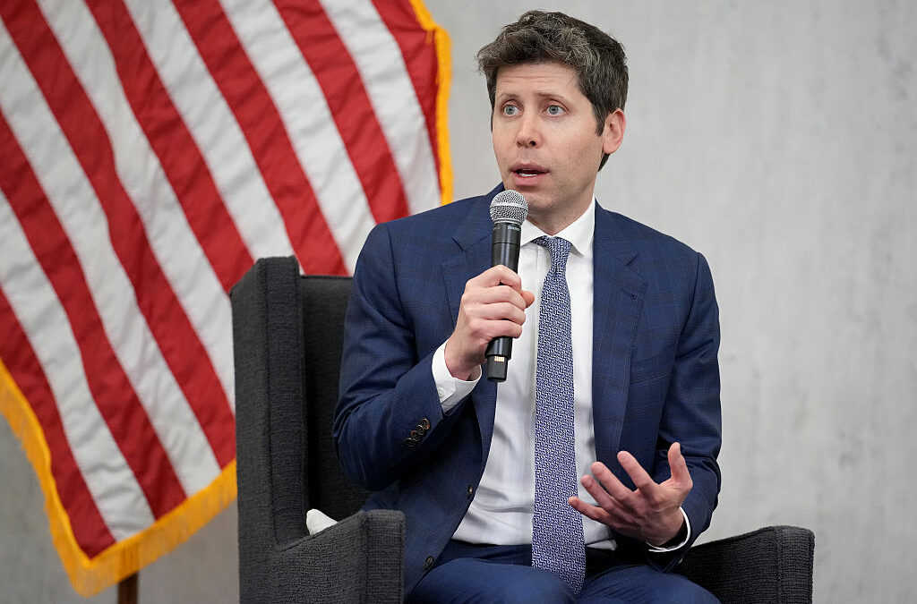 Sam Altman, CEO of OpenAI, sitting in front of American flag