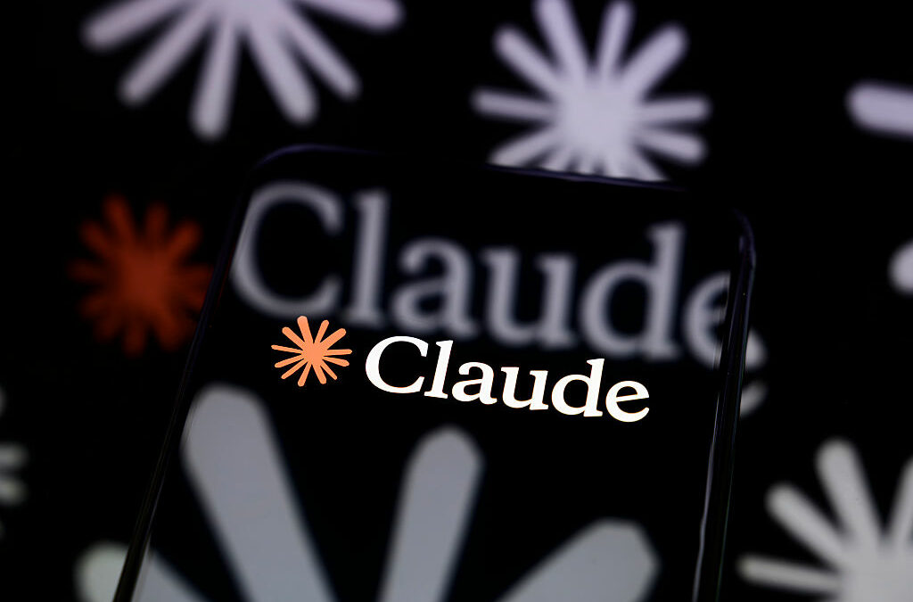 The Claude logo is displayed on a smartphone screen placed on a reflective surface onto which a multitude of Claude logos are projected.