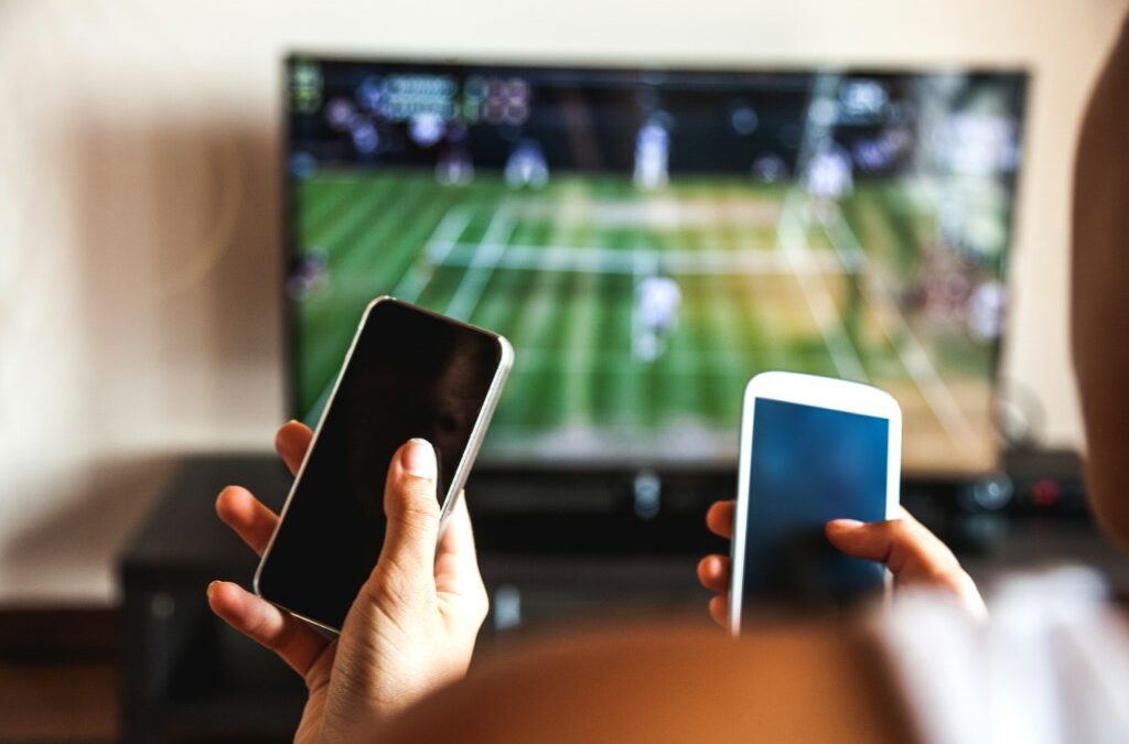 Friends using mobile phone during a tennis match on the TV.