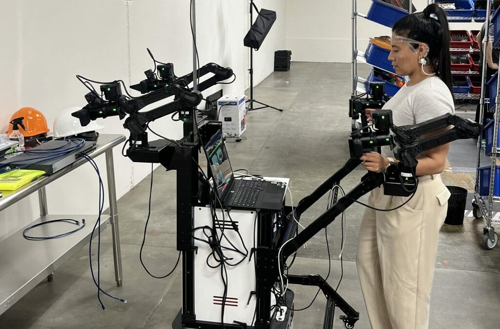 Senior Robot Pilot Sofia Infante operates a leader-follower rig to generate robot training data.
