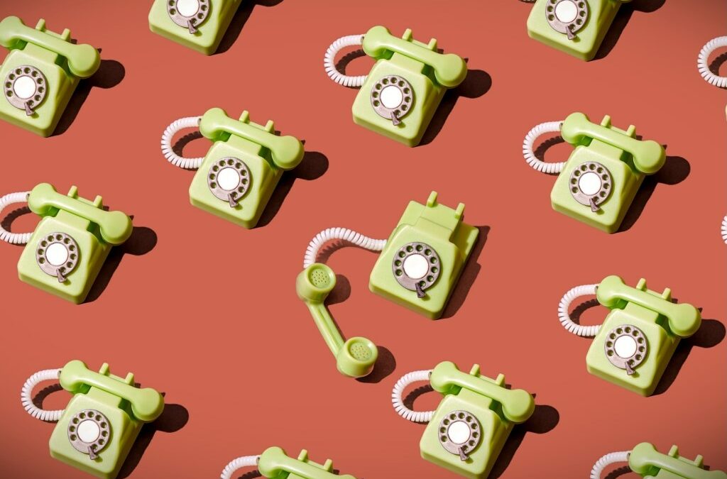 High angle view of some vintage green rotary telephones arranged on a brown background, showcasing retro communication technology with a nostalgic and artistic flair