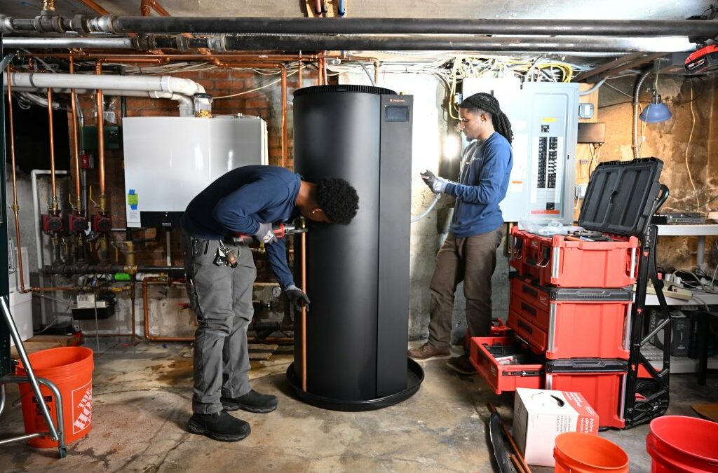 Two plumbers install a new water heater.
