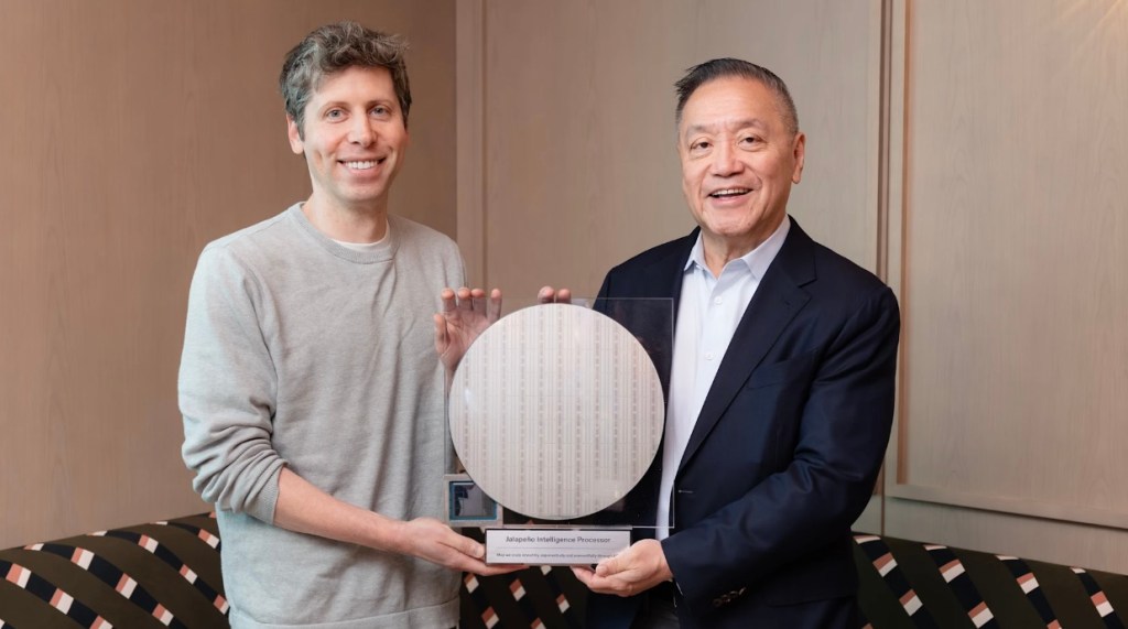 The CEOs of OpenAI and Broadcom stand flanking a circular semiconductor wafer.
