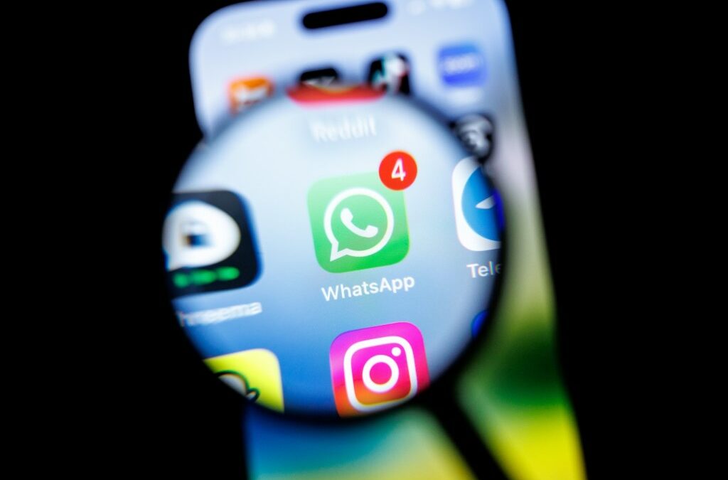in this photo illustration, the Whatsapp app logo can be seen through a magnifying glass on the display of a smartphone.